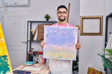 Young arab man artist smiling confident holding draw at art studio