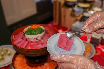 hands holding tuna sashimi at japanese restaurant