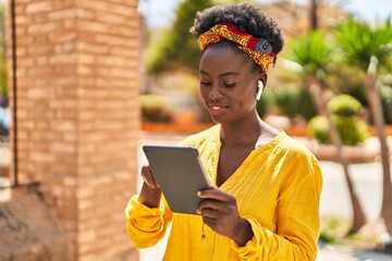 Young african american woman smiling confident using touchpad at street