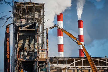 Hydraulic cutter destroys old building against chimneys
