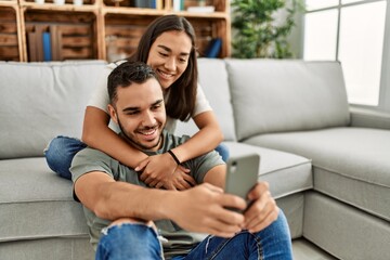 Young latin couple smiling happy making selfie by the smartphone at home. - obrazy, fototapety, plakaty