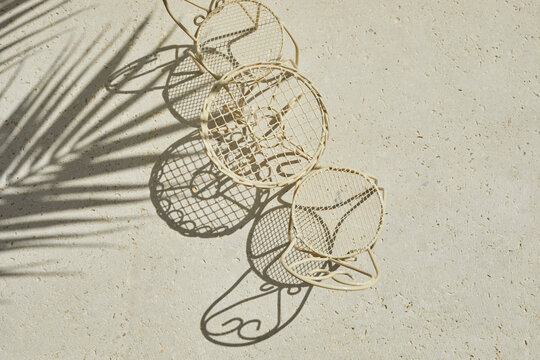 Metal table and chair on travertine stone background. Minimal layout with sunshine and hard shadow. Palm leaves shadow