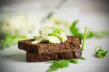 bread cheese spread with garlic and arugula on dark bread