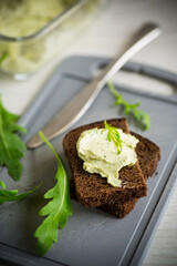 bread cheese spread with garlic and arugula on dark bread