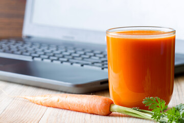 Carrot juice and laptop. Caring for eyesight while working with computer, concept - obrazy, fototapety, plakaty