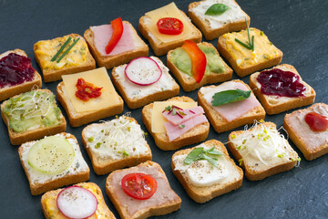 Set of mini sandwiches on black stone background