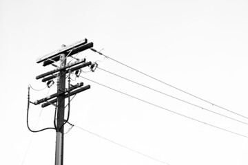 Low angle of a electric pole against a sky shot in grayscale