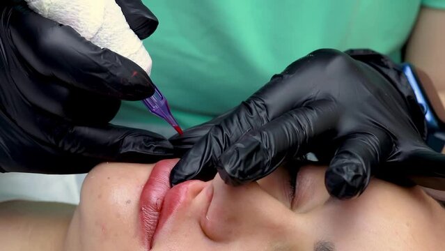 permanent lip makeup procedure the master performs tattooing on the device performs permanent lip makeup with red pigment