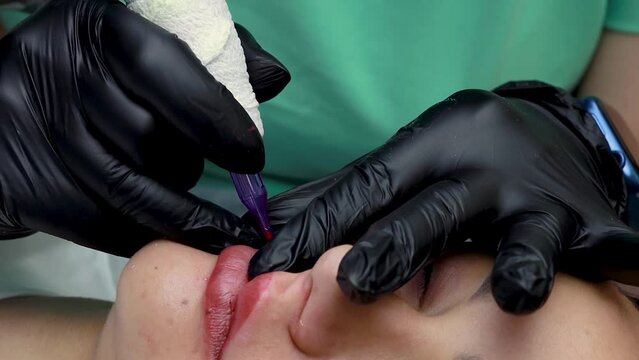 permanent lip makeup procedure the master performs tattooing on the device performs permanent lip makeup with red pigment