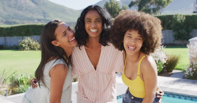 Portrait of happy diverse female friends smiling at swimming pool party