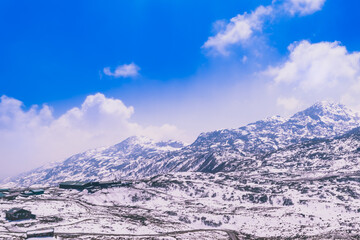 snow covered mountains and clouds over it.