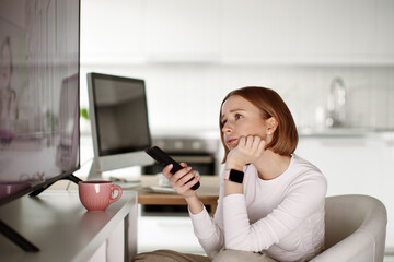 Woman watching tv, using remote control,  channel surfing, getting information and latest news,...