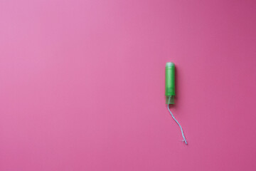 Green tampon with plastic applicator on pink background, flat lay with copy space, female hygiene, menstruation or women period, monthly bleeding, gynecology and healthcare, feminine blog template - obrazy, fototapety, plakaty