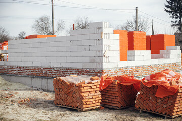 Building materials at construction site. Autoclaved aerated blocks on concrete foundation and...