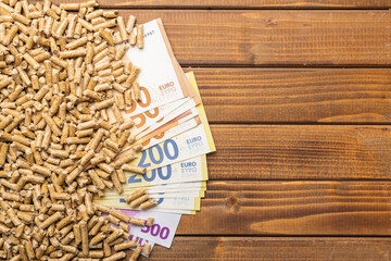 Wooden pellets and euro banknotes, biofuel on wooden table. Ecologic fuel made from biomass....