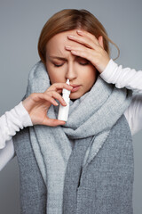Female wrapped in scarf using nasal spray medicine for runny nose . Seasonal health issues. Allergic chronic rhinitis, common cold, sinusitis concept. First symptoms of flu, virus or disease - obrazy, fototapety, plakaty