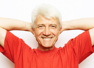 Handsome senior man wearing red t-shirt relaxing and stretching with arms and hands behind head and neck, smiling happy.