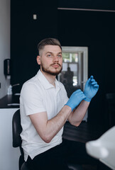 Male dentist putting on his gloves to work with his patients