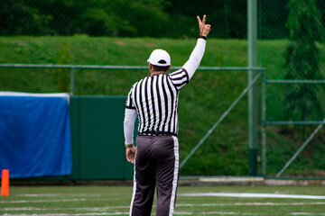 Back shot of a Male referee doing a fist sign during a Flag football match in the green field