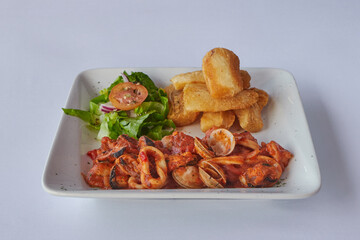 seafood in red sauce with salad and yucca