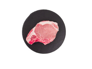 Raw pork steak on round black cutting board.