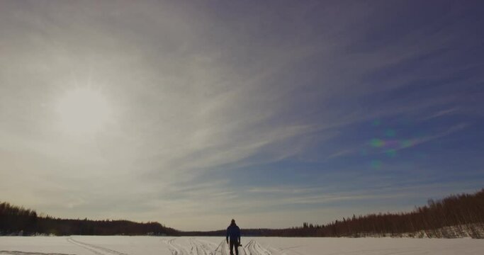Man looks up a the sky in a large snowy area in the Kenai National Wildlife Refuge, Alaska