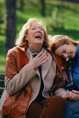 A grandmother is laughing and having fun with her adolescent granddaughter while sitting on the...