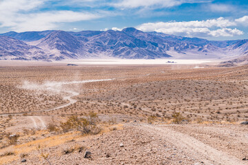 Vehicles travel down the gravel road towards the Racetrack Playa in Death Valley National Park