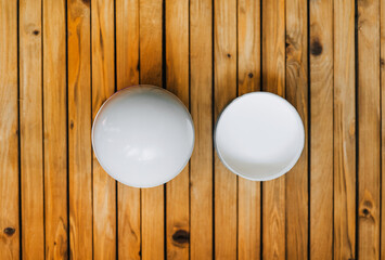 A round cardboard, paper white empty box and a glass lamp stand on a wooden background. Photography, copy space, concept. Choice, difference.