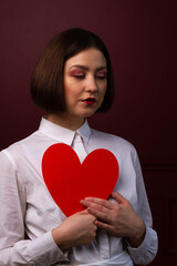 Dreamy short-haired woman holding heart shape in front of her chest