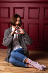 Short-haired woman in jacket shaping heart with fingers