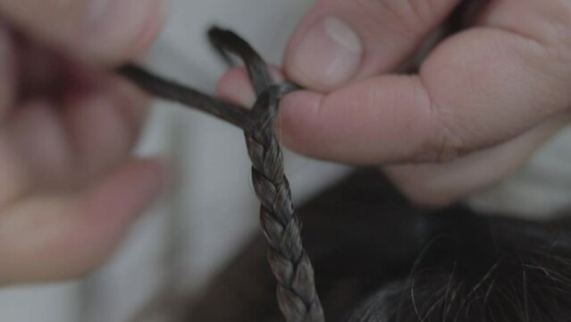 Manos confeccionando trenzas en cabello