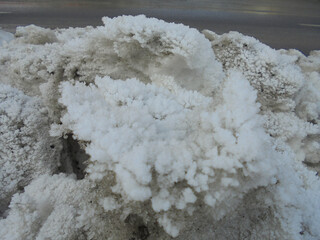 Massive heap of snow dirty from fumes piled up next to the road and covered by beautiful hoarfrost ice crystal structures resembling corals.