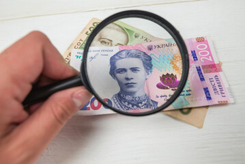 Close-up of the hryvnia under a magnifying glass. Financial concept.