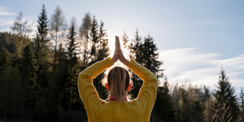 Woman in bright yellow sweater meditating in nature