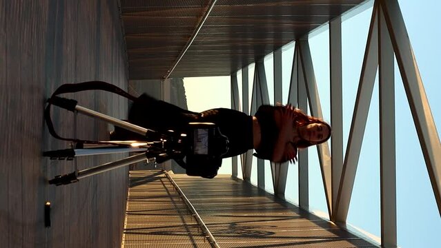 portrait of a young blonde Caucasian woman filming dance classes with her camera outdoors. joyful rhythm
