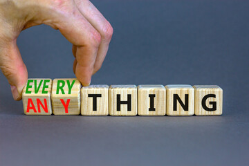 Anything or everything symbol. Businessman turns cubes and changes the concept word Anything to Everything. Beautiful grey background. Business motivational anything or everything concept. Copy space.