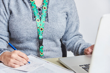 Woman studies or works using a sunflower lanyard, invisible disabilities symbol