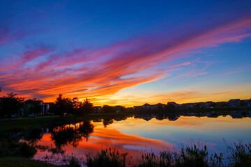 Beautiful pink, orange and blue sunset reflecting on a lake in a suburban neighborhood.