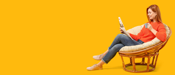 Beautiful woman drinking coffee and reading newspaper while sitting in cozy armchair against yellow background with space for text