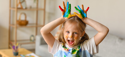 Funny little girl with palms in paint at home
