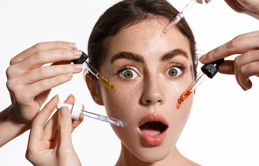 Skin care and rejuvenation. Beautiful Model With Radiant And Glowing Facial Skin Looking At Camera. Moisturizing With Serum Collagen And Hyaluronic Acid. Hands with serum dropper near girl face