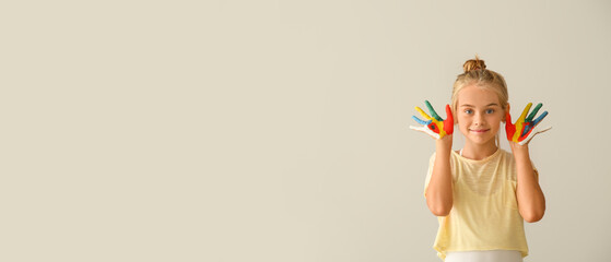 Cute little girl with hands in paint on light background with space for text