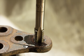 Cutting a thread in a hole with a tap by hand. Material high speed steel. We make an internal thread.