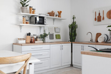 Light kitchen with modern furniture and pegboards near wall