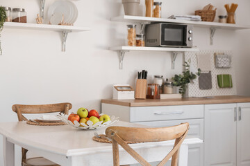 Fototapeta na wymiar Interior of light kitchen with fruit basket on dining table