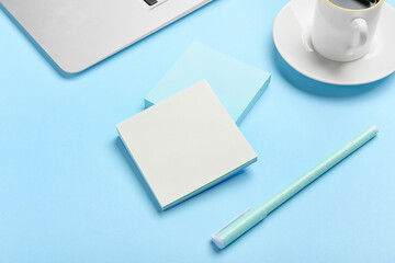 Blank sticky notes, pen and cup of coffee on color background