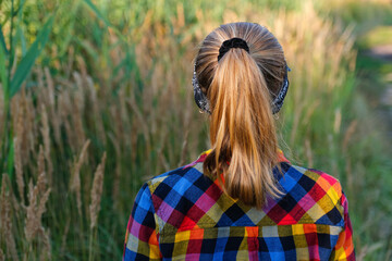 Defocus ponytail hairstyle. Teen or preteen girl walking on nature background and standing back....
