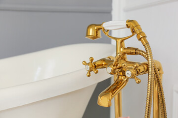 Golden shower faucet in bathroom, closeup