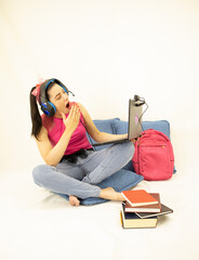 bored young student woman studying online with headphones, books, web camera, computer and backpack on white background
